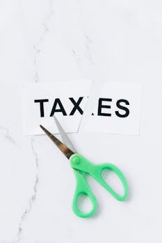 Close-up of scissors cutting the word taxes on a marble background, symbolizing tax reduction.
