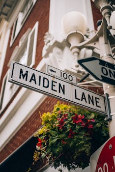 Street sign on Maiden Lane with flowers in a vibrant urban context.